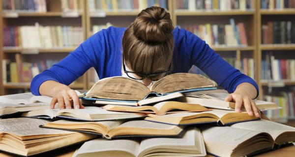 Girl studies for post-graduate degree with head in her books